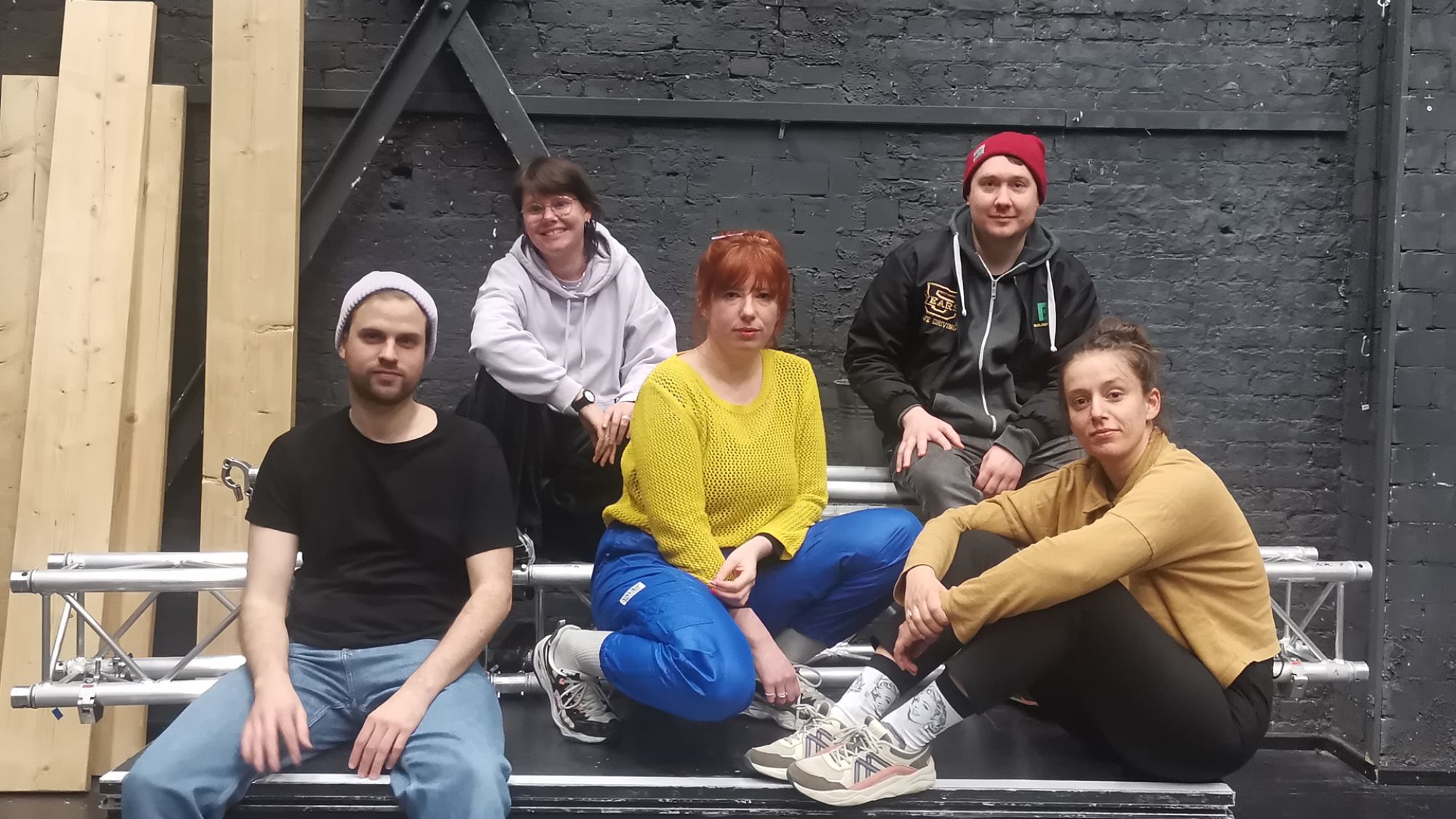 | | Fünf Menschen sitzen auf einem Podest und schauen in die Kamera.