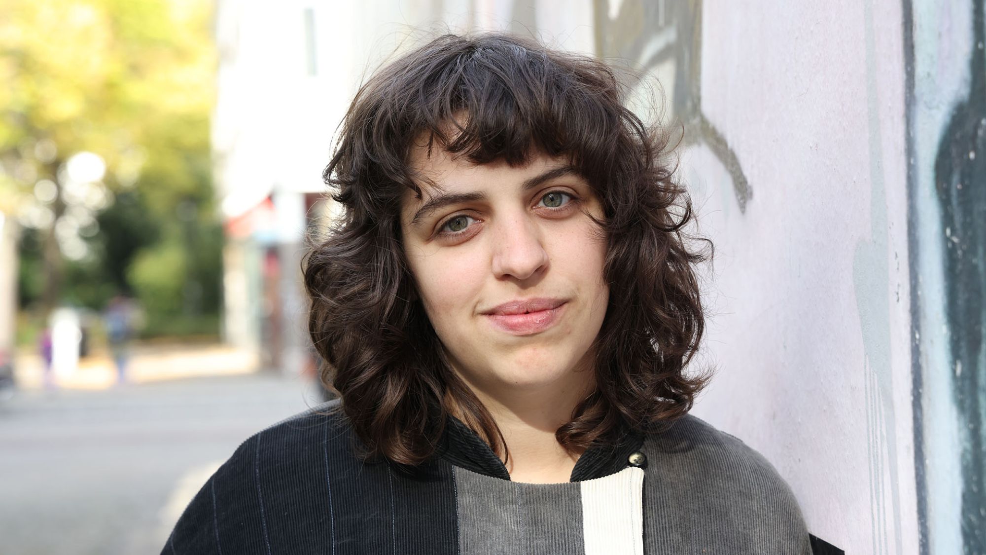 | | Eine Frau blickt in die Kamera.