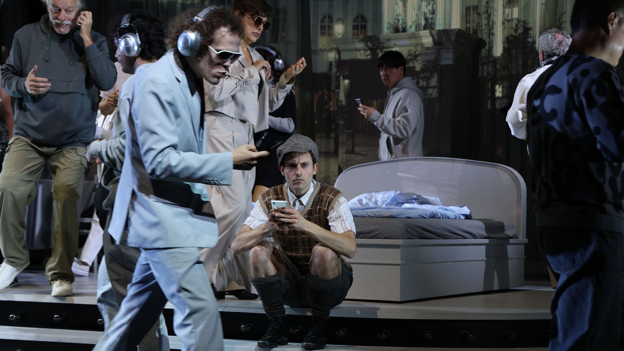 | | Eine Person sitzt auf einer Stufe und hält ein Handy in der Hand. Um sie herum sind viele weitere Menschen.