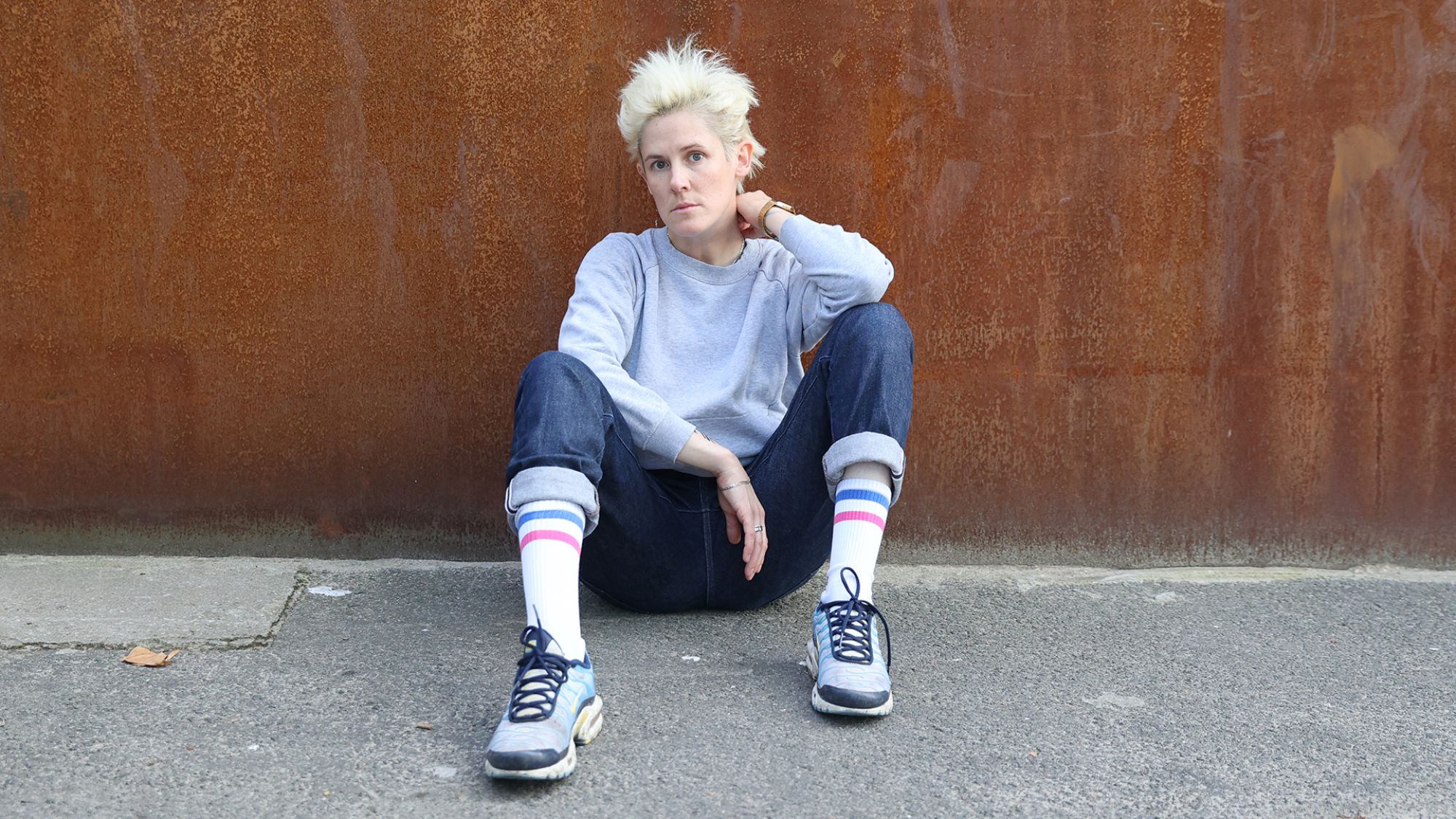 | | Dorothea Tuch Eine Person mit kurzen blonden Haaren sitzt auf dem Boden und blickt in die Kamera.