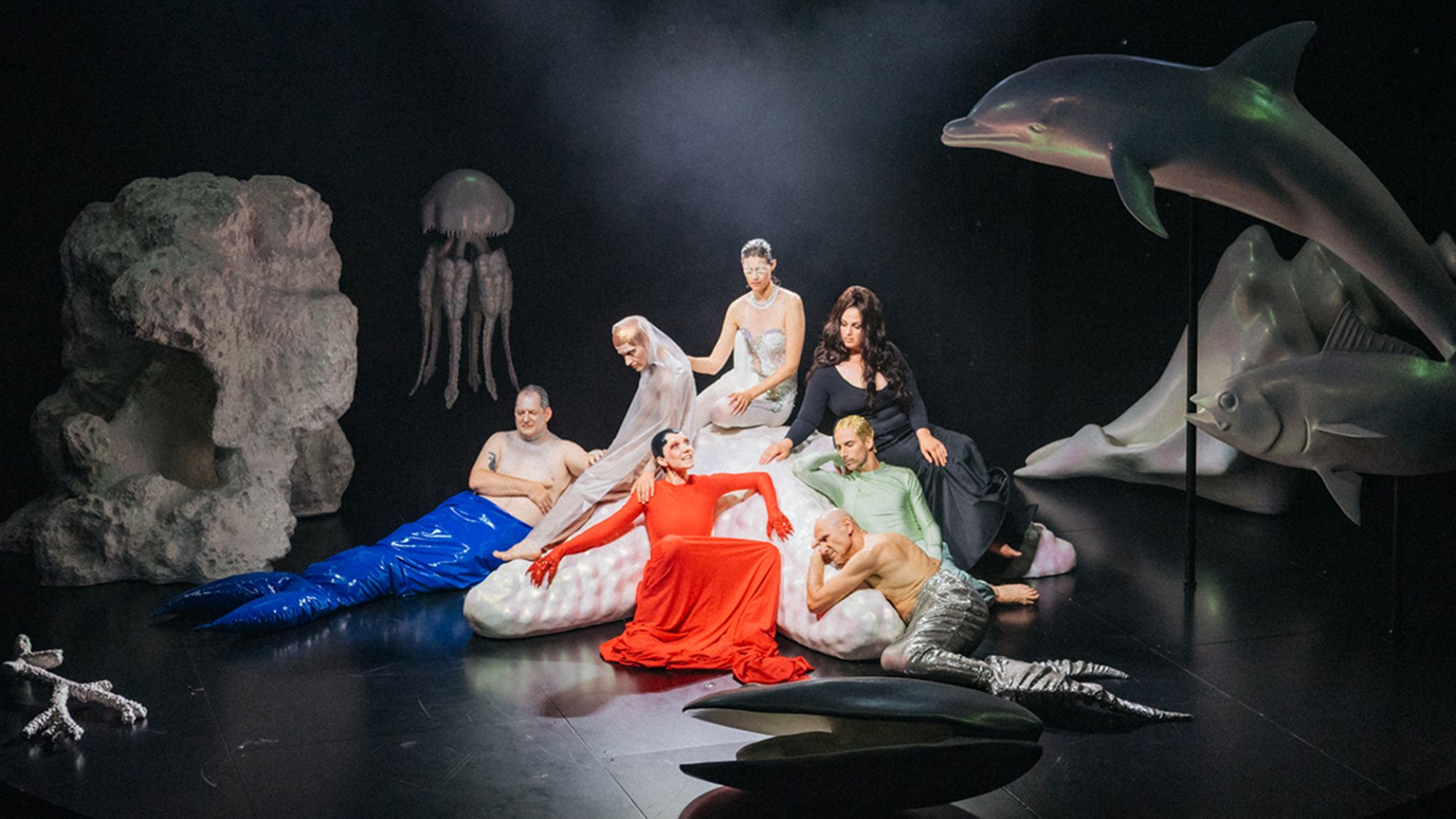 | | Philip Frowein In der Mitte der Bühne sitzen sechs Personen auf und um einen großen weißen Seestern. Manche tragen grellbunte Kostüme. Um sie herum stehen leuchtend weiße Meerestiere. Ein Delfin, eine Qualle, eine Muschel.