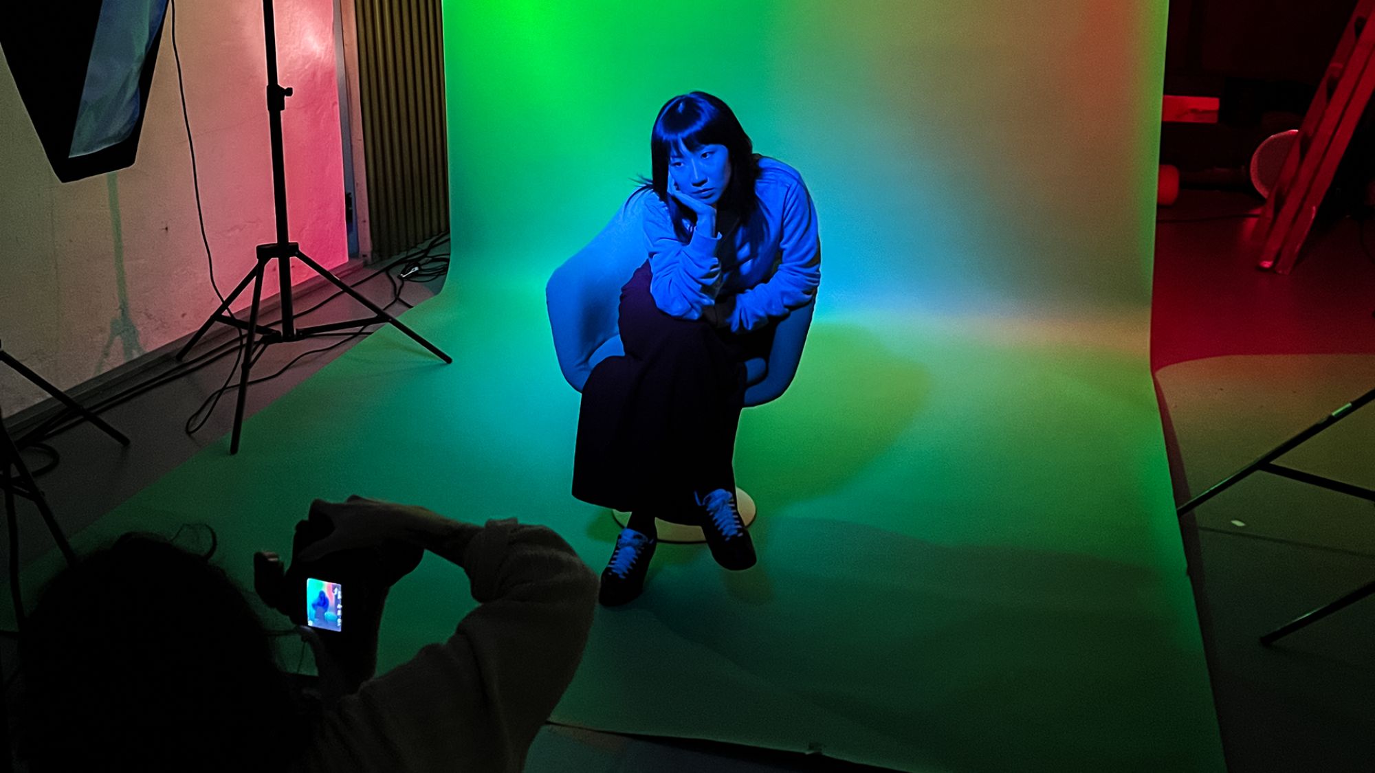 | | Eine Person sitzt auf einem Stuhl. Sie wird von einer anderen Person fotografiert.