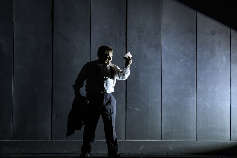 | © Bettina Stöß Mann im dramatischen Bühnenlicht hält mehrere Spielkarten in der Hand.