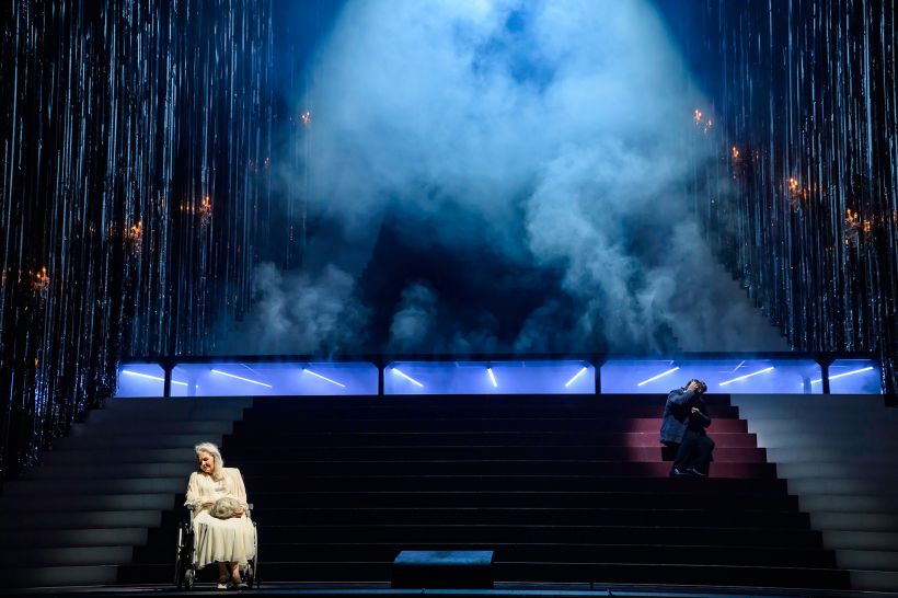 © Bettina Stöß Theaterbühne mit einer Frau im Rollstuhl, stufenförmiger Aufbau, viel Nebel und Lichtakzente.