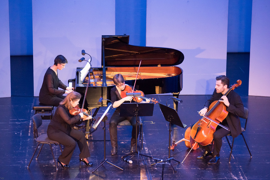 Ein Klavierquartett (Flügel, Violine, Viola, Violoncello) beim Musizieren im Rahmen eines Tischlereikonzertes.