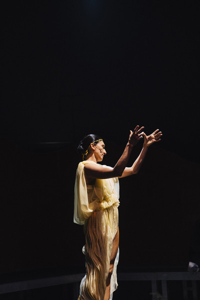 In einer cremefarbenen Toga mit antikem Faltenwurf tanzt eine Frau.