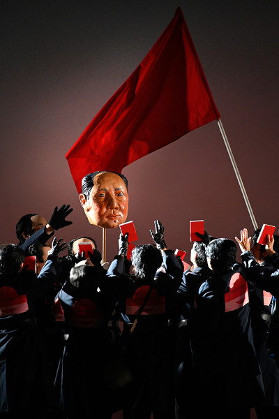 Eine Mao-Maske und eine rote Fahne weht über den Köpfen des chinesischen Volkes.