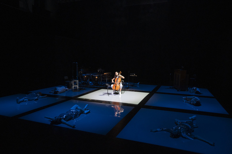 2023 fanden die letzten Neue Szenen statt. Auf diesem Bild ist eine Szene aus der ersten der drei Kammeropern: Physical Education. Ein Cellist sitzt in der Mitte der Tischlerei, um ihn liegen die Tänzer*innen noch am Boden.