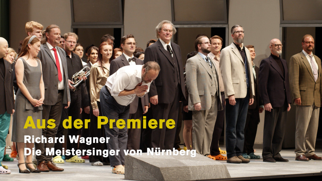 Dieses Foto ist das Standbild für das Video "Aus der Premiere". Alle Darsteller*innen nehmen den Endapplaus entgegen. Johan Reuter als Hans Sachs verbeugt sich.