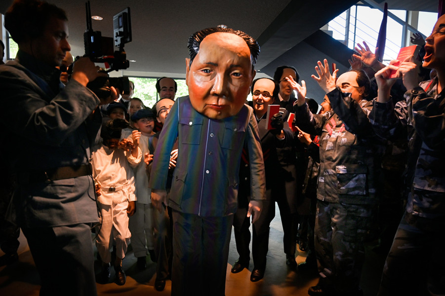Viele Darsteller mit chinesischen Masken sind jubelnd im Foyer.