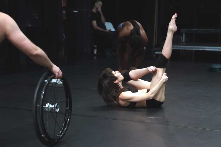 Eine Tänzerin liegt auf dem Boden und streckt ein Bein senkrecht nach oben. 
