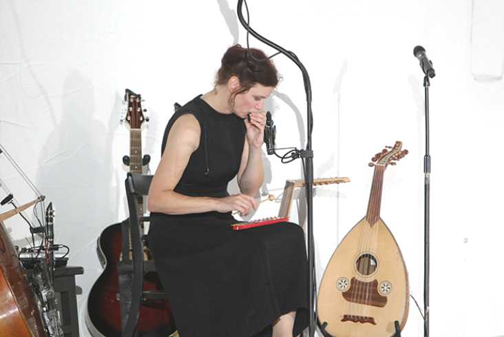 Eine Musikerin spielt auf einem kleinen Xylophon. Um sie herum stehen Instrumente.