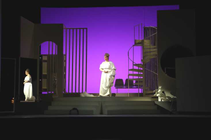 Eine Sängerin steht in einem weißen Abendkleid mitten auf der Bühne. 