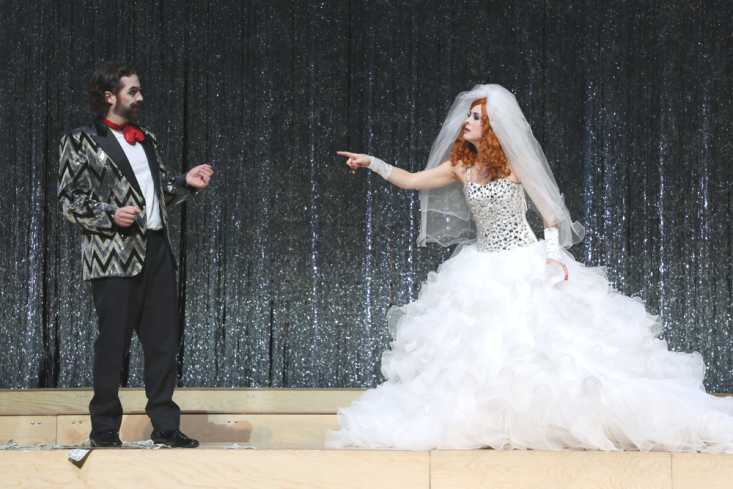 Ein Mann in einem Anzug und eine Frau in einem Hochzeitskleid stehen sich gegenüber und diskutieren.