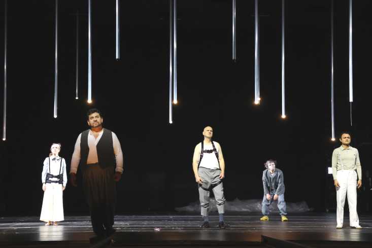 Fünf Personen stehen auf der Bühne. Aus dem Bühnenhimmel hängen schwache Lichter.