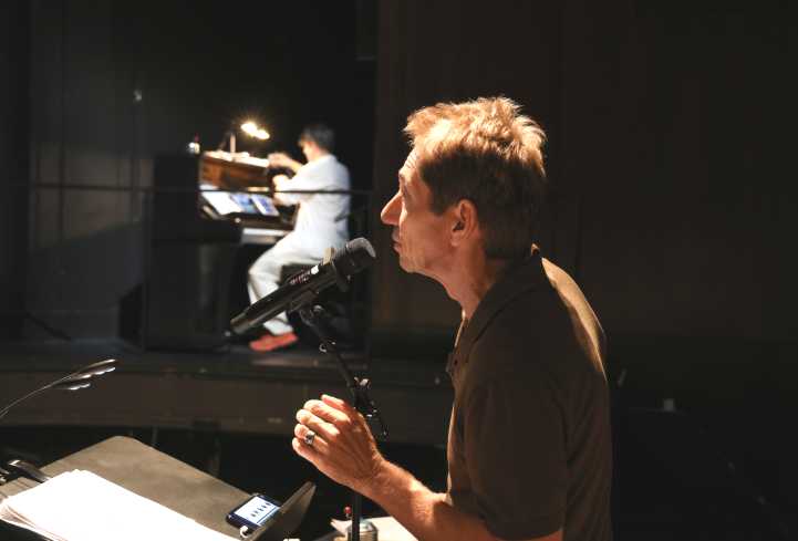 Schorsch Kamerun steht am Mikrofon. Im Hintergrund sieht man PC Nackt an einem Klavier.