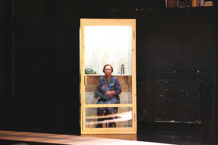 Eine Frau sitzt in einer umgebauten Telefonzelle.