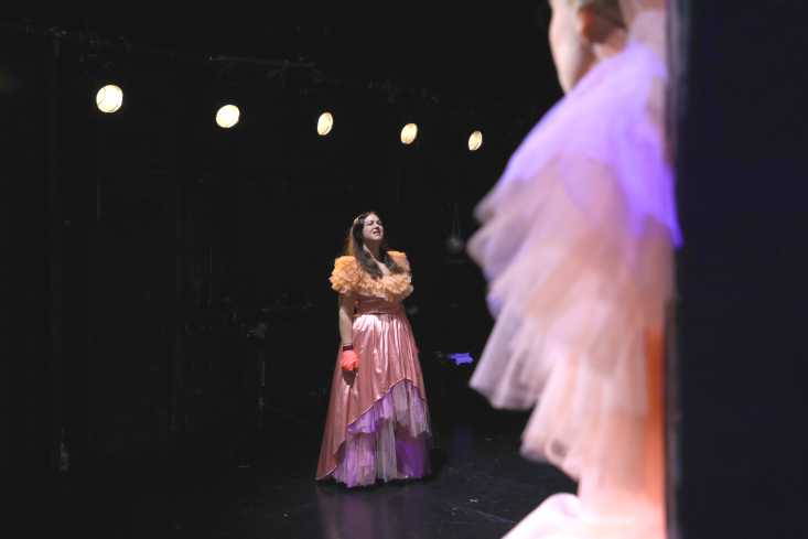Eine Schauspielerin in einem bauschigen Kleid steht auf der Bühne.