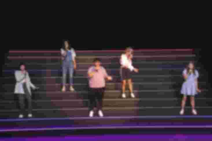 Fünf Jugendliche stehen auf einer großen Treppe und singen.