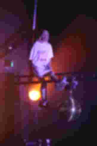 Ein Schauspieler schwebt auf einer Traverse über die Bühne. Er trägt ein übergroßes T-Shirt mit Kapuze und Fellhausschuhe. 