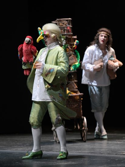 TITLE: Das Märchen von der Zauberflöte
URHEBER: Bettina Stöß Papageno und Tamino im Gespräch über Schlangenbändigung und mehr. Ein zartgrünes Kostüm kleidet Papageno, in hellblau und weiß ist Tamino gekleidet. Rokoko wird zitiert mit Kniebundhosen, Seidenstrümpfen, Schnallenschuhen, großen Ärmelaufschlägen und Volants am Hemd.