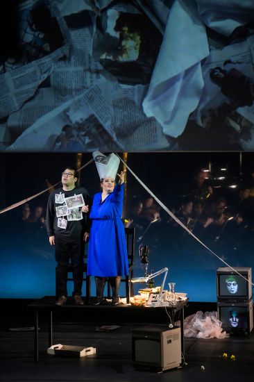 TITLE: Aida
URHEBER: Bettina Stöß Amneris hat sich auf Zeitungen einen Pharaonen-Hut gebastelt und steht gemeinsam mit Radames auf dem Essenstisch wie auf eine Bühne. Er hat die Zeitungsausrisse auf seine Brust geheftet.