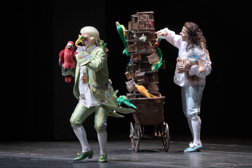 TITLE: Das Märchen von der Zauberflöte
COPYRIGHT: Bettina Stöß Tamino und Papageno machen sich gemeinsam auf den Weg, Pamina zu befreien. Die Kostüme zitieren Rokoko. Wenige Requisiten verdeutlichen kindgerecht das Geschehen. Auf einem Handkarren stapeln sich zahllose Vogelkäfige mit Vögeln aus Plüsch darin. Tamino hält als Zeichen seiner Kindlichkeit einen Plüschbären im Arm, Papageno einen Plüschpapageien.