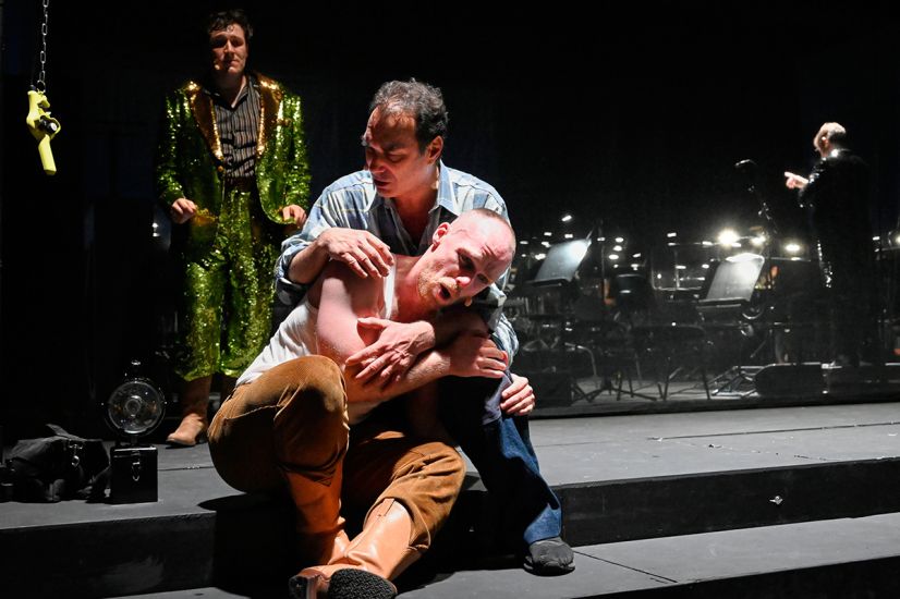 TITLE: Aufstieg und Fall der Stadt Mahagonny
URHEBER: Thomas Aurin Jimmy hält Alaskawolfjoe im Arm. Hinter den beiden Sparbüchsenbill.