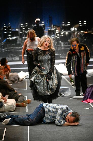 TITLE: Aufstieg und Fall der Stadt Mahagonny
URHEBER: Thomas Aurin Jimmy ist tot. Von hinten kommen in seine Richtung Begbick, Fatty und Dreieinigkeitsmoses.