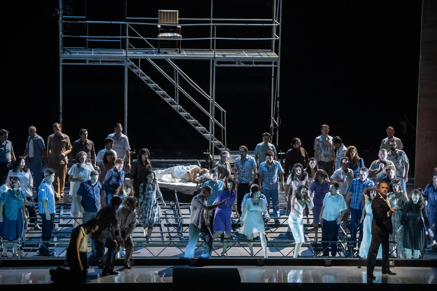 Turandot - © 2023 // Bettina Stöß Die Bühne ist derangiert. Die Wand ist gefallen. Davor das Volk und Calaf. In den Trümmern des Bühnenbildes schläft Turandot. Im Hintergrund ein Gerüst mit einer Plattform, zu der eine Treppe führt. Auf der Plattform steht ein leerer Lehnstuhl.