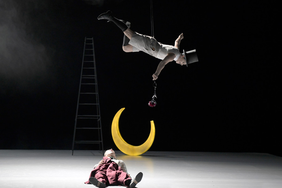 A Midsummer Night’s Dream - © Bettina Stöß Lysander liegt schlafend auf der Bühne. Puck nähert sich ihm. Die Leiter steht im Hintergrund. Eine goldene Mondsichel steht am Boden.