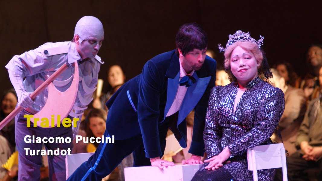 Giacomo Puccini: Turandot (2023) - © Ruth Tromboukis Dies ist ein Standbild zum Trailer. Ping, Pang und Pong spielen die sich immer wieder vollziehende Köpfung des Brautwerbers dem Volke vor.