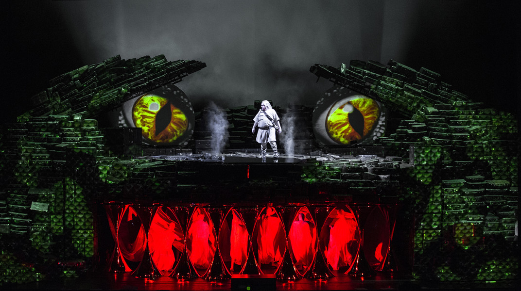 Siegfried - © Bernd Uhlig Eine Szene aus SIEGFRIED (Siegfried mit dem großen Drachen). Der Jüngling droht, dem Drachen zu Leibe
zu rücken, brächte dieser ihm das Fürchten nicht bei. Mit Licht, Projektionen und Menschen in weißen Hüllen entsteht der Drache auf der Bühne. Siegfried steht zwischen dessen Augen.