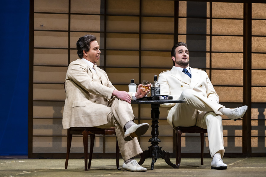 Madama Butterfly - © Bettina Stöß Pinkerton und Sharpless im Gespräch. Sharpless weist Pinkerton darauf hin, dieser möge nicht zu sorglos mit dem Prinzip der Ehe auf Zeit umgehen, aber Pinkerton verwirft die Sorgen. Sie sitzen in weißen Leinenanzügen an einem Kaffeehaustischchen, darauf Whisky.