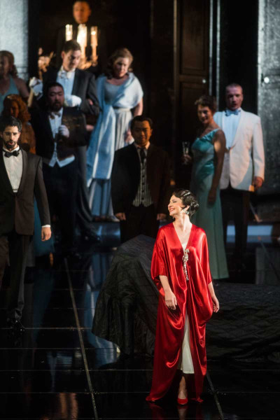 La Traviata - © Marcus Lieberenz Violetta auf ihrem Fest: Sie trägt den roten Seidenmantel und ist üppig mit Diamanten geschmückt. Um sie herum die Festgesellschaft.