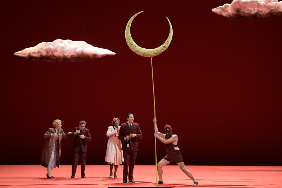 A Midsummer Night’s Dream - © Bettina Stöß Die "bürgerlichen" Paare treten auf, um am Herzogshof zu feiern: Lysander und Hermia, Demetrius und Helena. Außerdem kommt schon der erste Schauspieler der Truppe: Der Darsteller des Mondes. Die bürgerlichen Paare tragen Kostüme der 30ger Jahre, die Herren Uniformen wie ihr Herr, die Damen Mäntel und Kleider in unauffälligeren Farben wie rosa oder zartlila. Der Schauspieler trägt eine rote Skimaske, einen roten Ringeranzug und einen Stab, auf dem der Mond angebracht ist. Über allem schweben rosa Wölkchen.