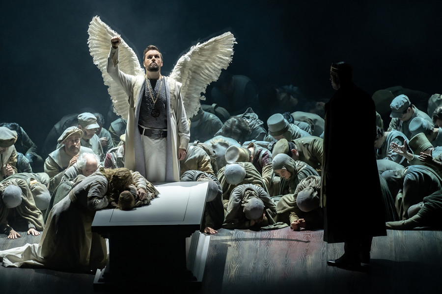Lohengrin - © Bettina Stöß Es ist das Finale. Lohengrin verabschiedet sich aus Brabant, er streckt die Faust gen Himmel. Vor dem Sarkophag kniend umarmt Elsa verzweifelt die Leiche ihres kleinen Bruders . König Heinrich steht betrachtend rechts neben dieser Szenerie. Der Chor liegt und kniet, den Blick zu Boden gerichtet.