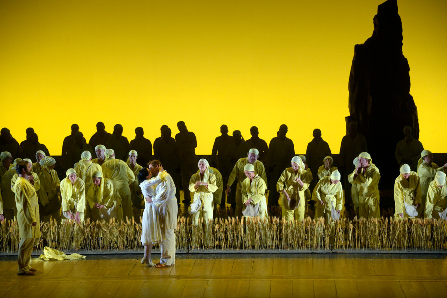 Die Zauberflöte - © Bettina Stöß Der Horizont ist im Finale in strahlendes Sonnengelb getaucht. Vor dem Horizont ragt ein Felsen in die Höhe. Davor der Chor und Sarastro in sonnengelben Kleidern. Tamino und Pamina küssen sich.