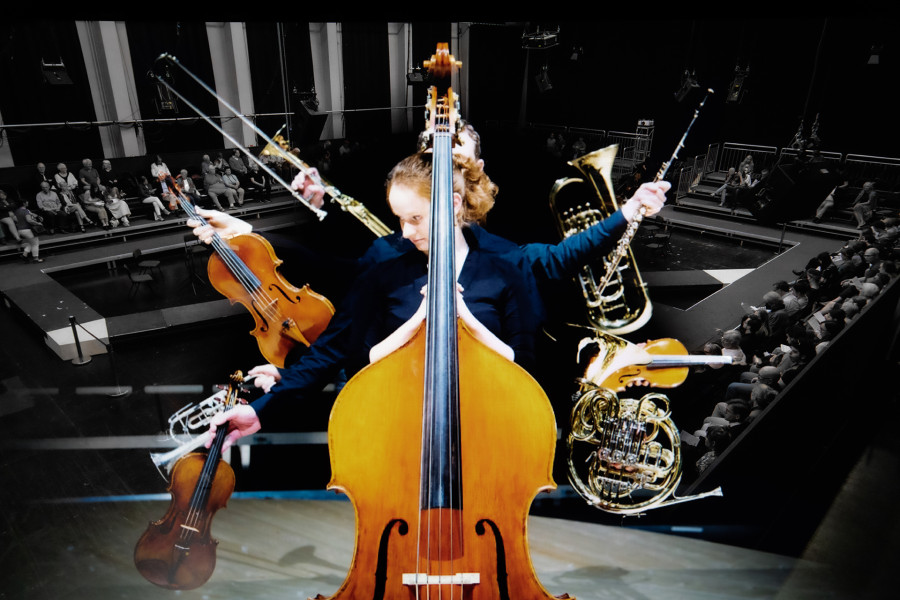 Auf diesem Bild, das das Akademistenkonzert bebildert, steht eine junge Musikerin hinter einem Kontrabass. Weitere Instrumente ragen ins Bild.