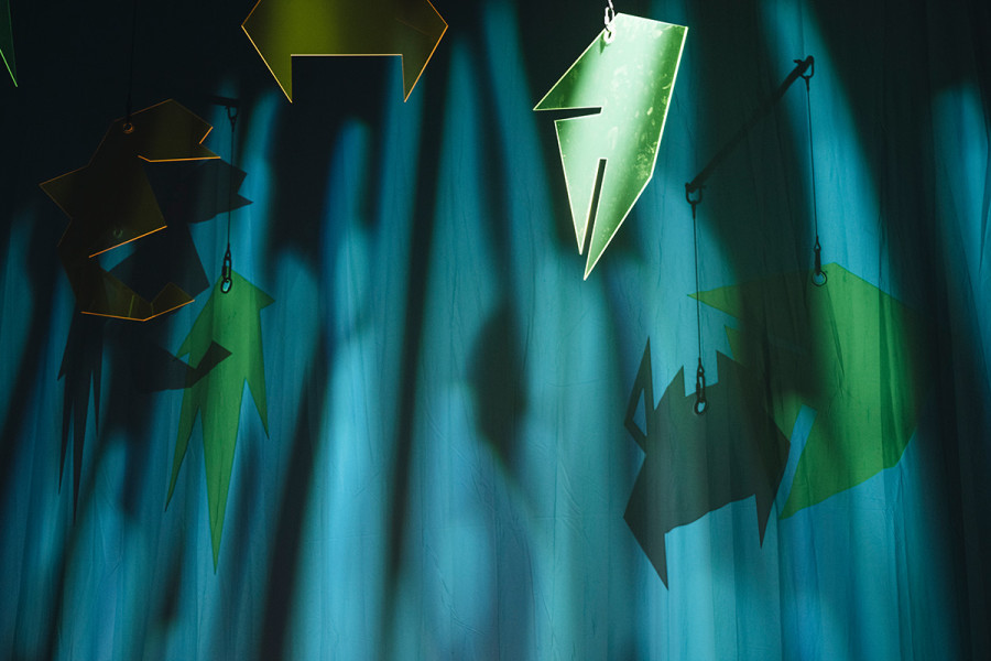 Tintenfischlady -   © Nancy Jesse  Eine Detail aus dem Bühnenbild: Ein wassergrüner Vorhang und ein Glasmobile mit abstrakten grünen Fischen.