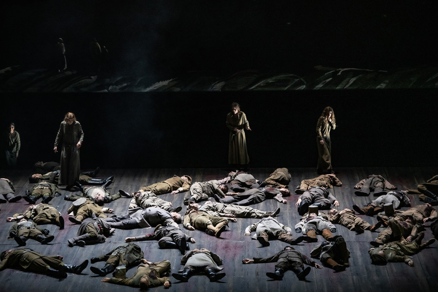 Lohengrin - © Bettina Stöß Auf dem Boden liegen zahllose gefallene Krieger. Von hinten steigen Frauen auf, die gefallenen Söhne und Männer zu identifizieren versuchen.