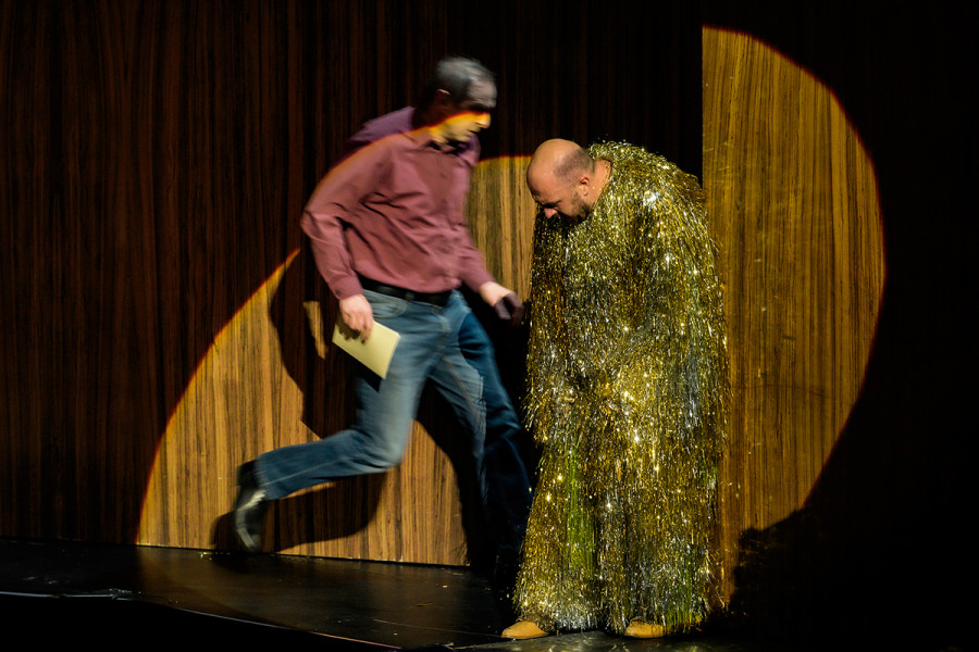 Rigoletto - © Bettina Stöß Versunken in wütende Einsamkeit steht Rigoletto im Lamettagewand am Bühnenportal. Die Kappe mit den Hasenohren ist abgenommen.