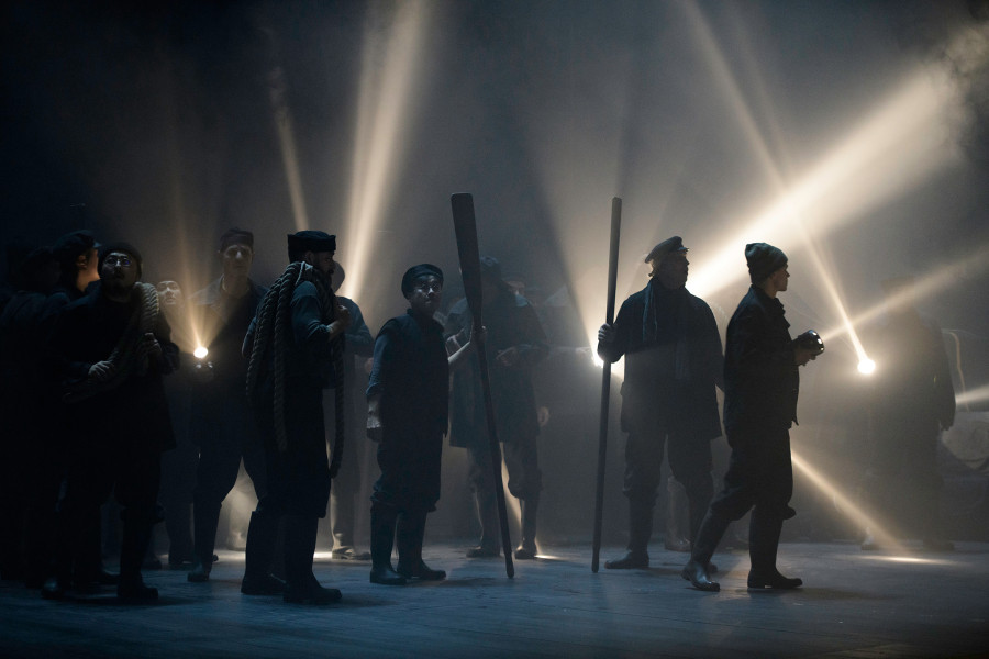 Der fliegende Holländer - © Bettina Stöß Sänger des Chores kommen auf die Bühne. Sie haben schwere Regenschutzkleidung an, manche tragen Ruder und Schiffstaue mit sich, andere Taschenlampen, die Lichtkegel in die nebelige Bühne werfen.