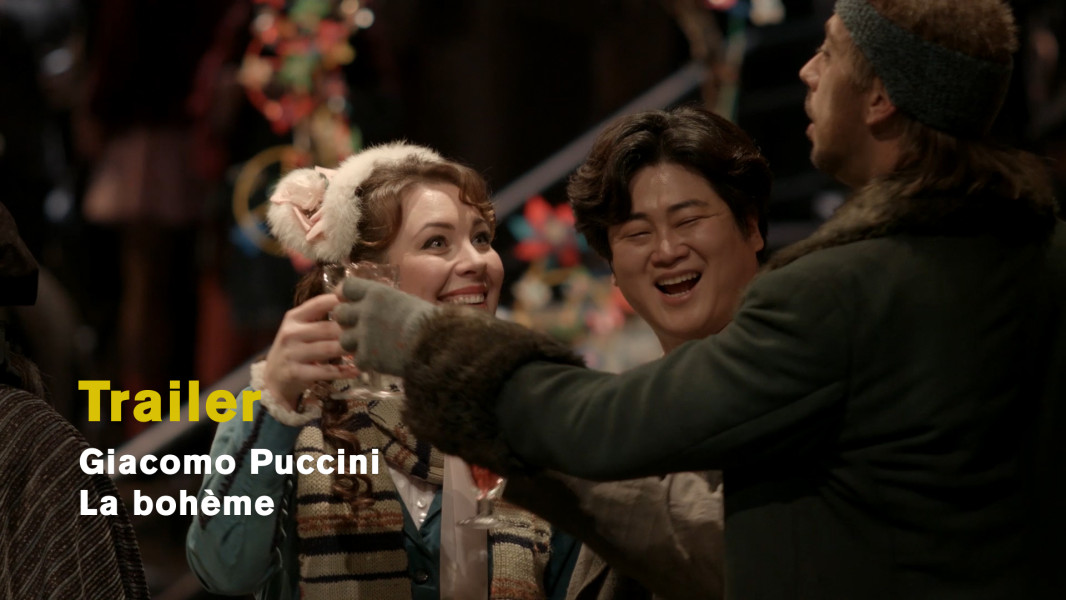 Giacomo Puccini: La Bohème - © Ruth Tromboukis Dieses Foto ist das Standbild zum Videotrailer mit Stückimpressionen aus Götz Friedrichs Inszenierung. Mimì mit Ohrwärmern feiert ausgelassen und glücklich mit den Freunden Rodolfos im Quartier Latin.