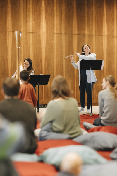 Babykonzert - © Nancy Jesse Eine Flötistin und eine Harfenistin beim Babykonzert. Auf Sitzkissen das kleine Publikum,