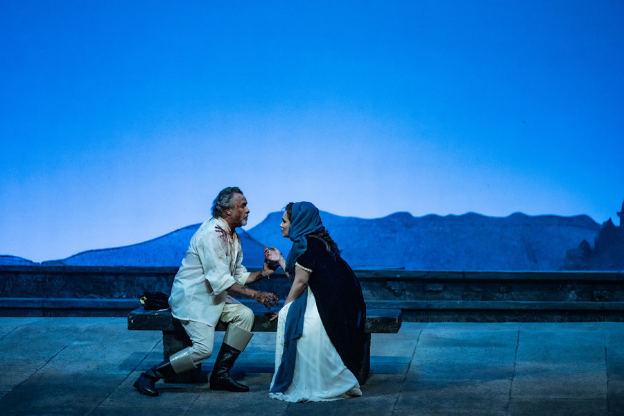 Tosca - © 2023, Bettina Stöß Der Morgen dämmert über der Engelsburg. Auf einer Steinbank sitzend sind Tosca und Cavaradossi ins Gespräch vertieft.