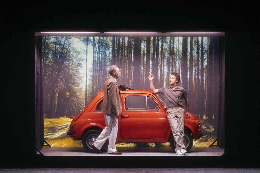 Die Verführung des Vaters: Christoph Schlemmer als Paolo, Nikolay Borchev als Ospite vor einem roten Fiat