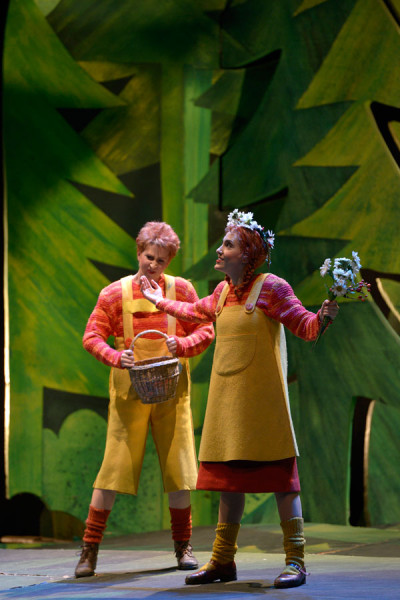 Hänsel und Gretel sind inzwischen im Märchenwald angekommen: Ihre Kleider haben sich magisch verändert. Sie tragen fröhliche rote und orange Kleidung. Gemeinsam sammeln sie Blumen und Erdbeeren
