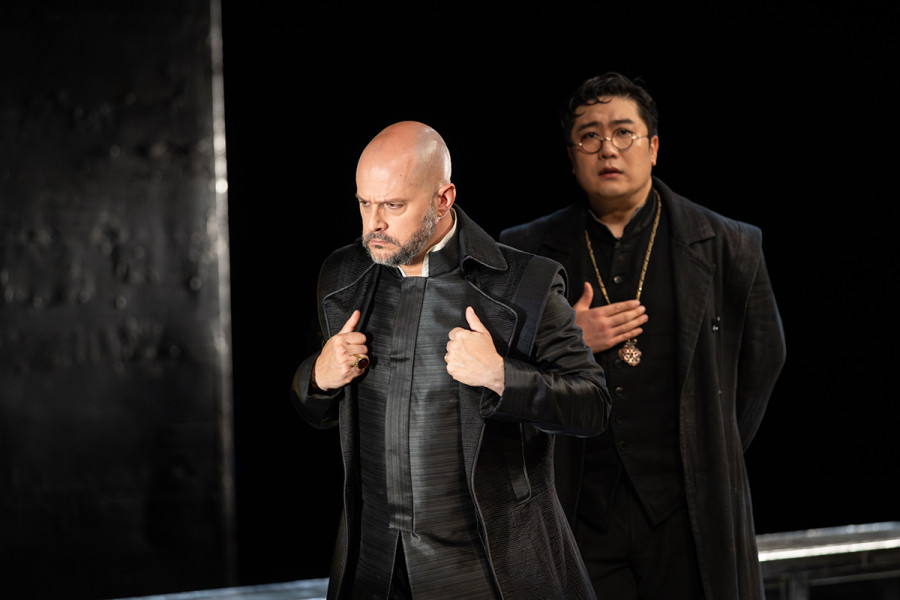 Don Carlo - © Marcus Lieberenz Mit gramvoll zurückgehaltener Wut blickt Philipp vor sich auf den Boden. Hinter ihm, auf ihn einredend Rodrigo. Rodrigo erzählt von den unhaltbaren Zuständen in Flandern.