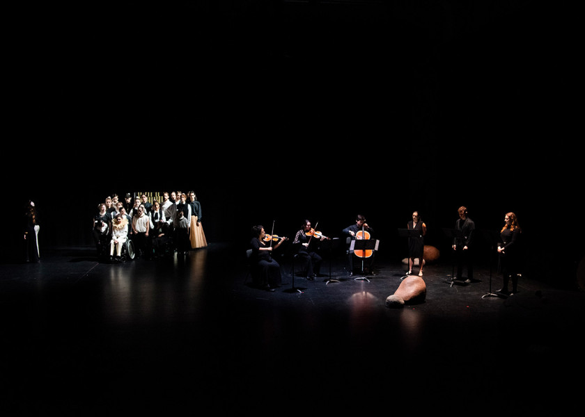 Eine Bühnentotale: Links bilden die Darsteller*innen des Jungen Ensembles eine Gruppe, rechts stehen die Künstler*innen, die Arvo Pärts Werk interpretieren.